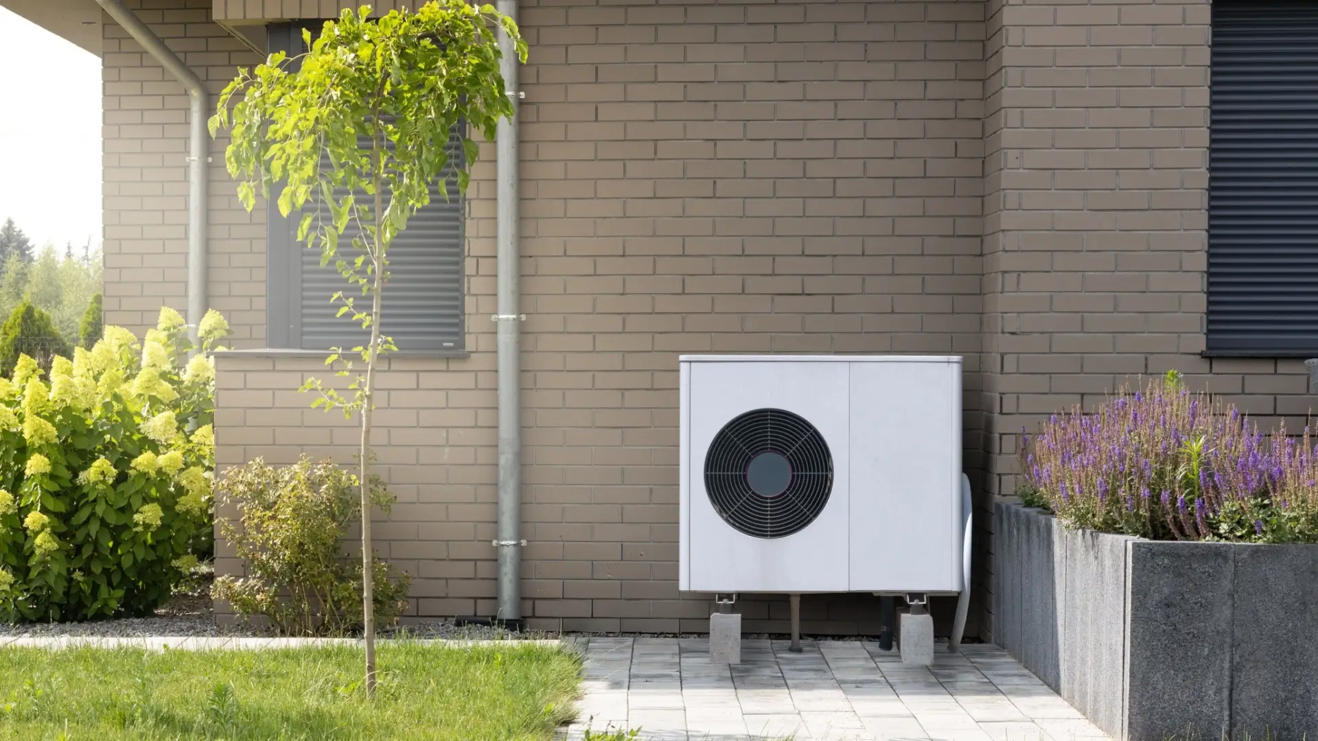 Außengerät einer Wärmepumpe neben Wohnhaus